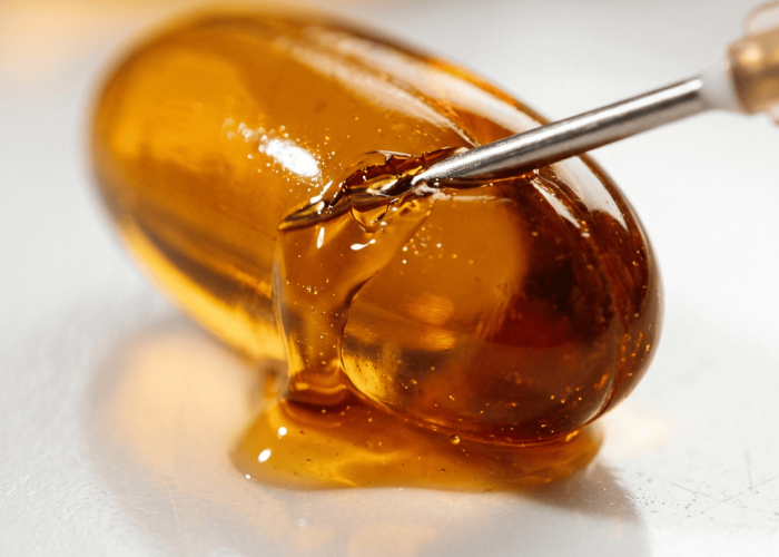 Vitamin E capsule with rich golden oil flowing out on white surface