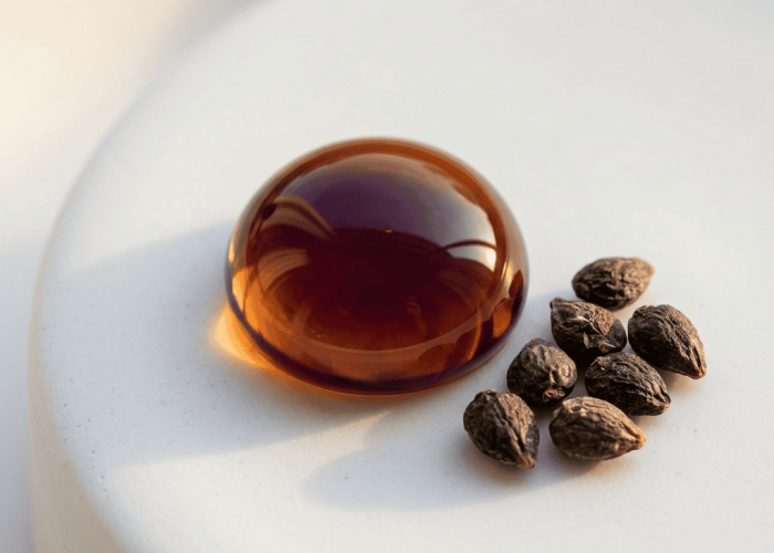 Deep amber bakuchiol extract drop on white porcelain with dried babchi seeds
