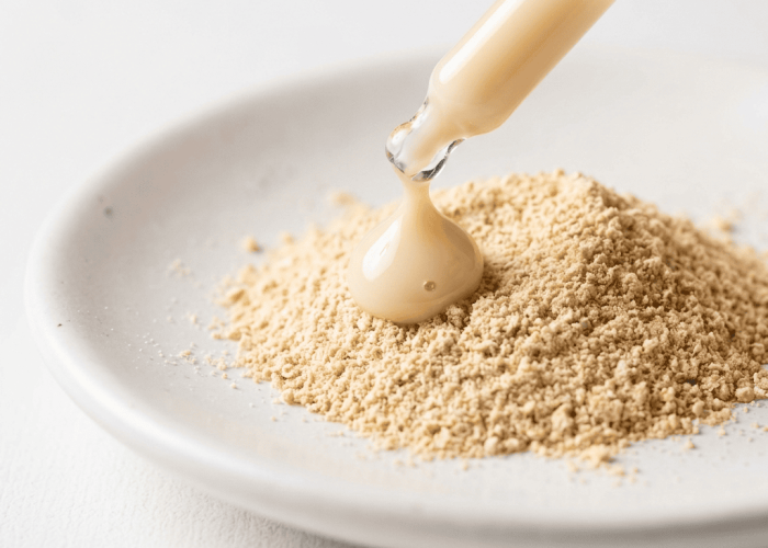 Creamy oat milk drop on fine colloidal oatmeal powder on white ceramic dish