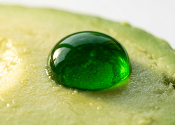 Rich green avocado oil drop on smooth avocado flesh glowing under warm light