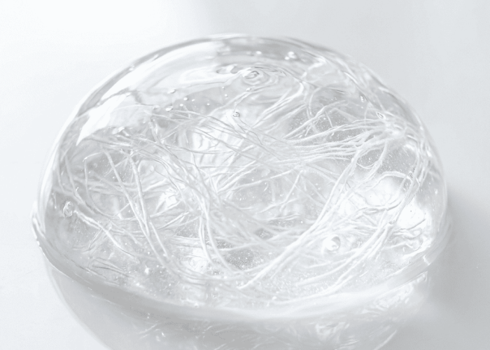 Clear collagen gel with visible fibrous protein strands on white glass surface